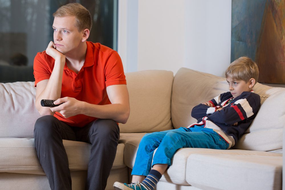 a dad and child watching tv and bored