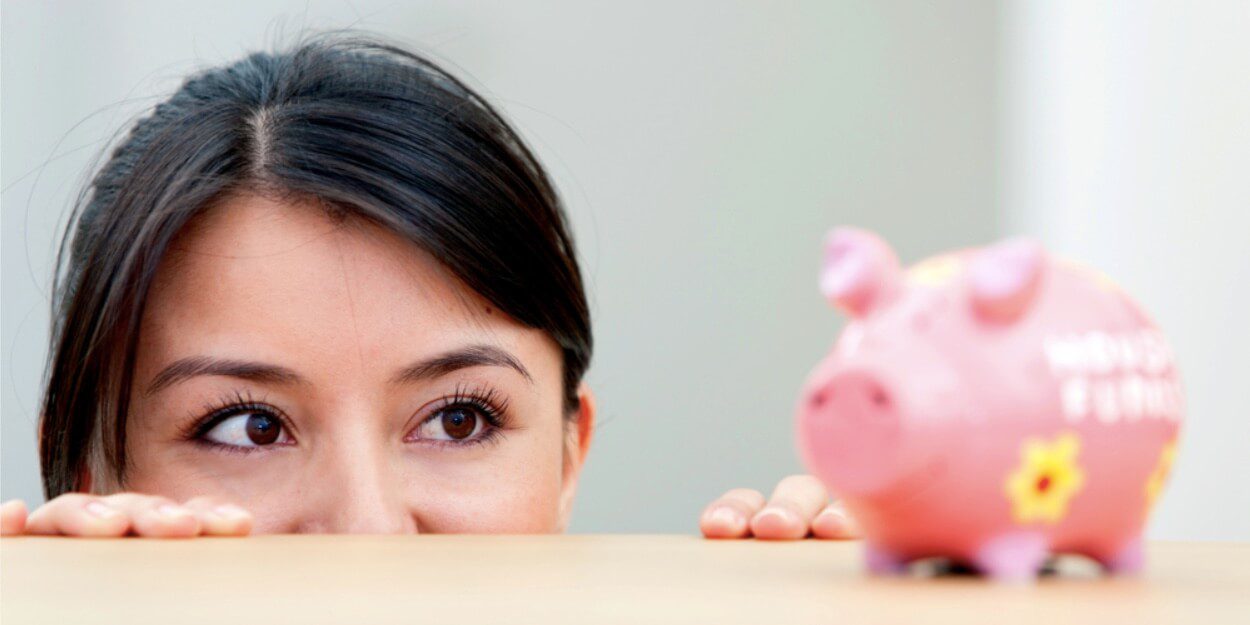 person looking on a small pink piggy bank