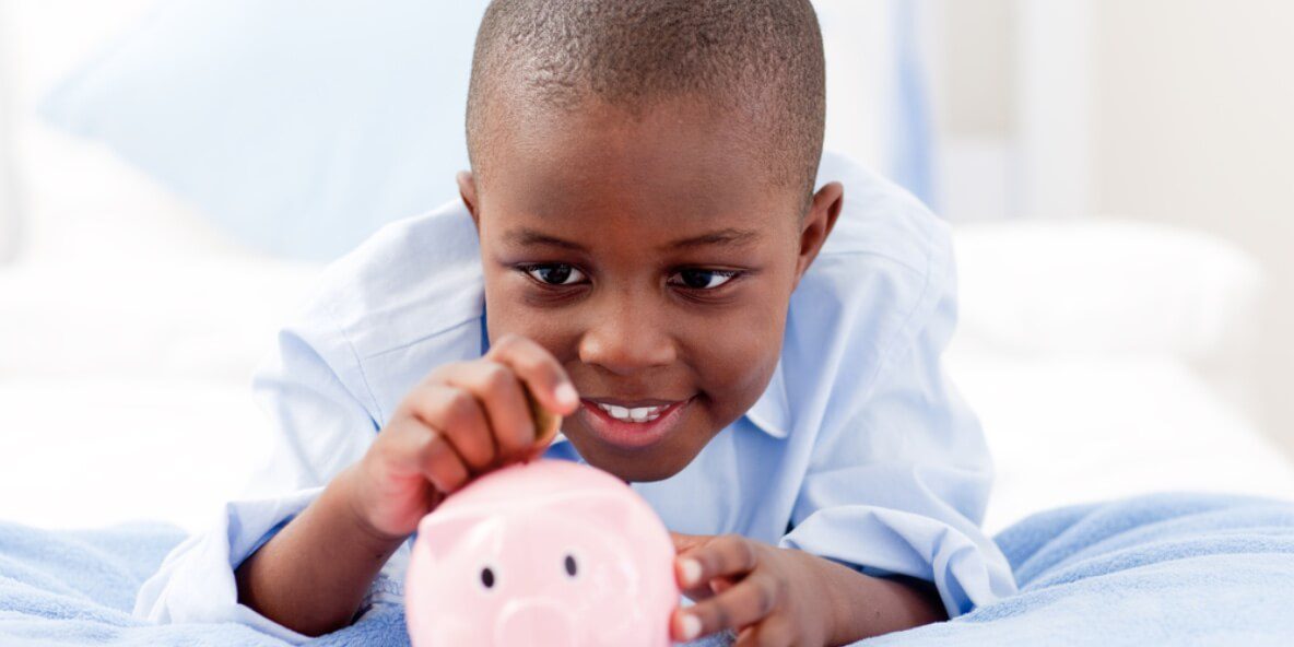 a black child putting money on piggy bank
